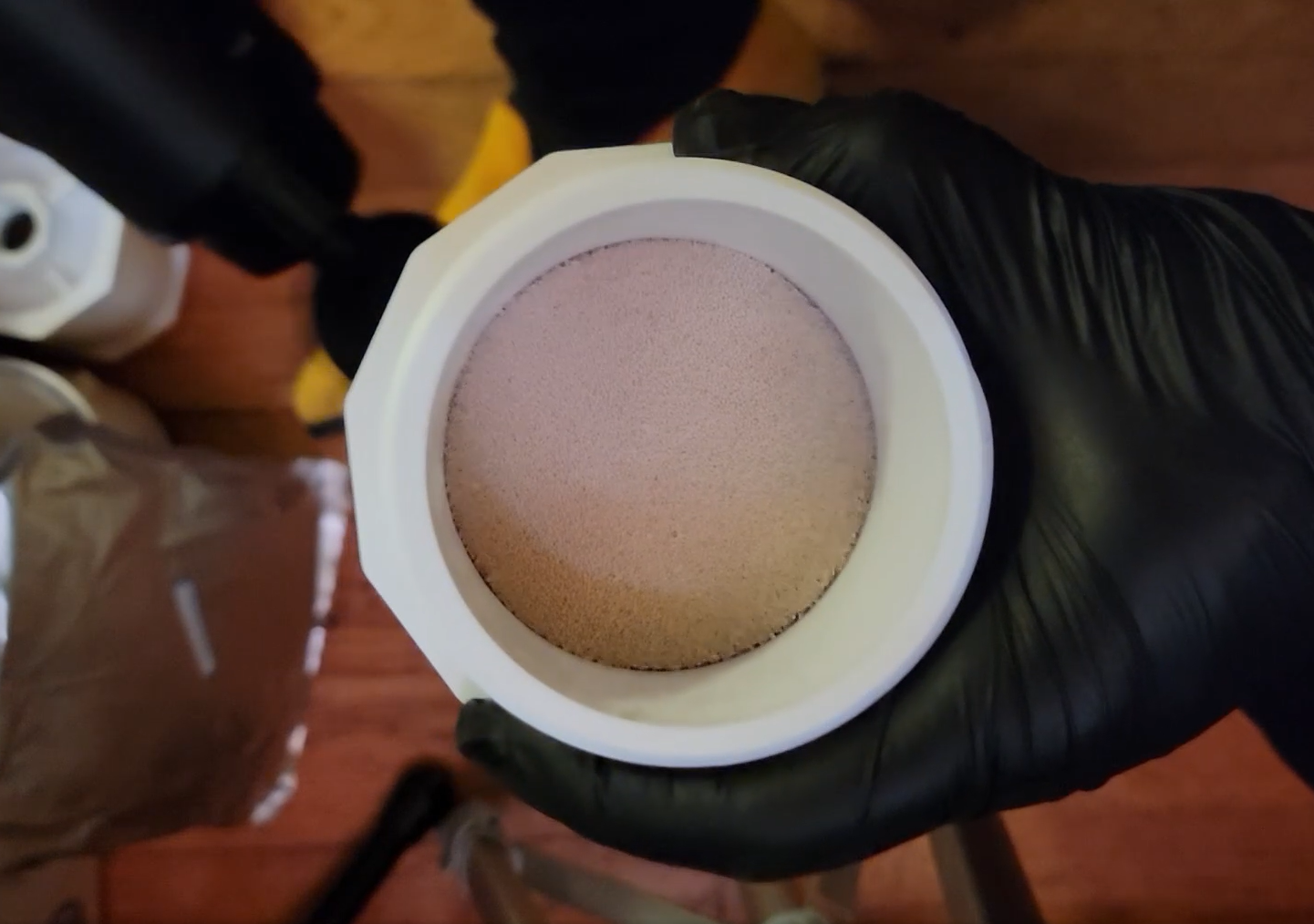 Top down view of a canister filled with molecular sieves being vibrated with a massage gun